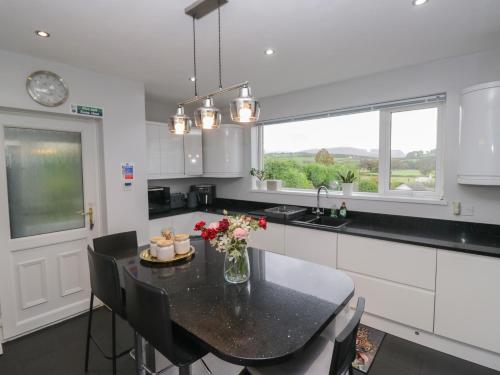 a kitchen with a table with a vase of flowers on it at Eildon Lodge in Seascale