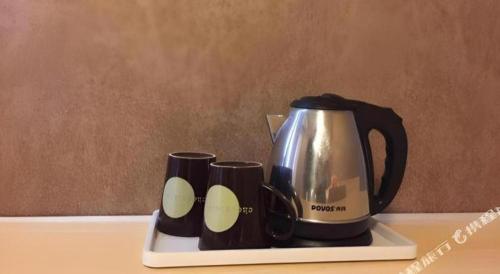 a coffee pot and cups on a tray on a table at 7 Days Inn Qingdao Liaoyang West Road Xinye Plaza Metro Station in Qingdao