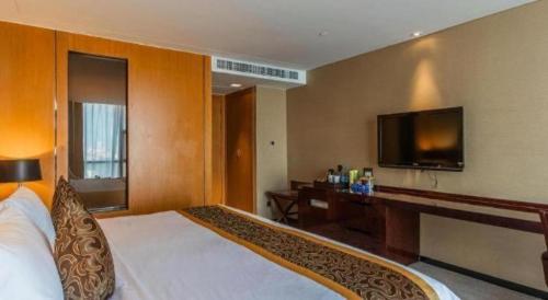 a hotel room with a bed and a flat screen tv at Zhangjiagang Zhonglian GDH International Hotel in Zhangjiagang