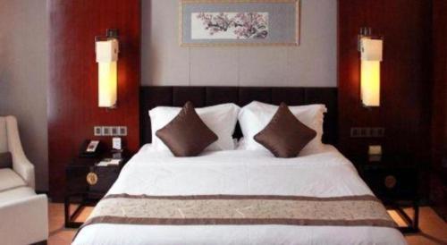a bedroom with a white bed with two pillows at Zhangjiagang Zhonglian GDH International Hotel in Zhangjiagang
