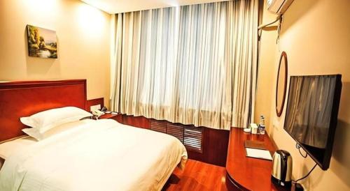 a bedroom with a bed and a flat screen tv at GreenTree Inn Xinjiang Uygur Autonomous Region Korla Bazhou Bus Terminal Beishan Road Express Hotel in Korla