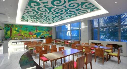 a restaurant with tables and chairs and a mural at Harbin Ju Jian Hotel in Harbin