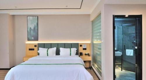 a bedroom with a large white bed and a bathroom at GreenTree Inn Suzhou Shihu Suli Road Express Hotel in Suzhou