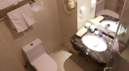 a white bathroom with a sink and a toilet at GreenTree Inn DingZhou Railway Station Business Hotel in Baoding