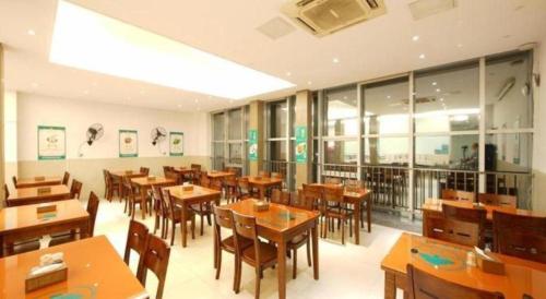 a restaurant with wooden tables and chairs and windows at GreenTree Inn Fujian Fuzhou Software Park River View Business Hotel in Fuzhou