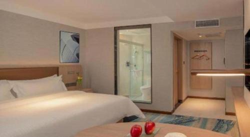 a bedroom with a large white bed and a bathroom at GreenTree Inn Ganzhou Sankang Temple DaRunFa Express Hotel in Ganzhou