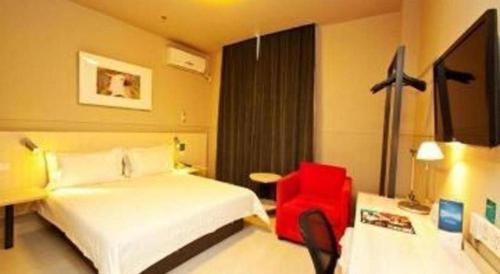 a hotel room with a bed and a red chair at Jinjiang Inn Linyi Jinqueshan Road Branch in Linyi