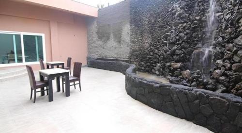 a table and chairs next to a wall with a fountain at Sea View Hotel in Jeju