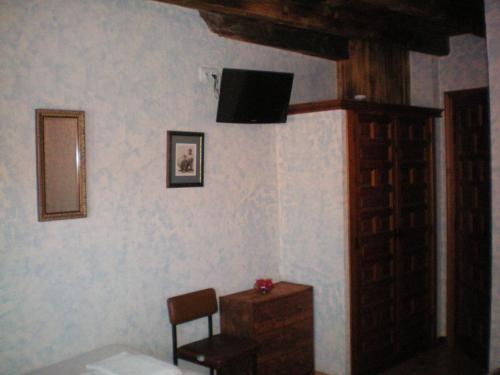 Habitación con silla y TV en la pared. en Hotel Rural Los Perales en San Vitero