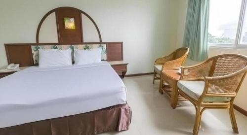 a bedroom with a large bed and two chairs at Lake Inn Hotel in Songkhla