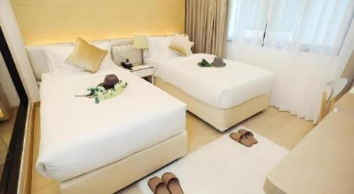 a hotel room with two beds and some shoes at Thaisun Bangkok Hotel in Bangkok