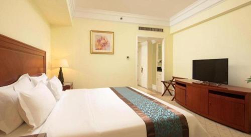 a bedroom with a large bed and a flat screen tv at Changshu Jinling Tianming Grand Hotel in Suzhou
