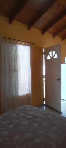 a bedroom with a bed and a window and a door at La Gringa in Villa Elisa