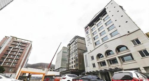 a tall building with cars parked in a parking lot at Nostalgia Hotel in Paju