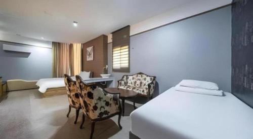 a hotel room with a bed and chairs and a desk at Nostalgia Hotel in Paju