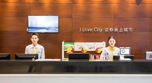 two women wearing yellow ties sitting at a counter at City Comfort Inn Beihai RT-Mart High Speed Railway Station in Beihai