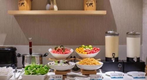 a kitchen counter with bowls of food on a table at City Comfort Inn Beihai RT-Mart High Speed Railway Station in Beihai