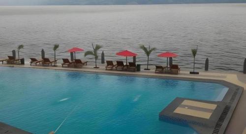 a swimming pool with chairs and umbrellas next to the water at Samosir Cottages Resort in Tuk Tuk