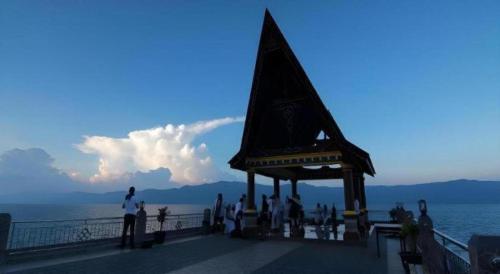 a group of people standing on a pier near the water at Samosir Cottages Resort in Tuk Tuk