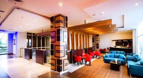 a living room with blue furniture and red chairs at Ayola First Point Hotel Pekanbaru in Pekanbaru