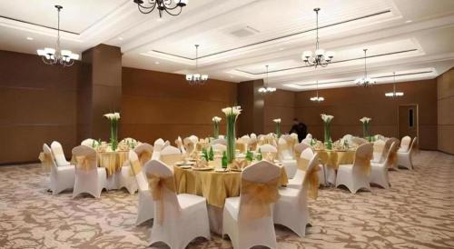 a banquet hall with white tables and white chairs at Hotel Grandhika Pemuda in Semarang