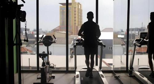 a person standing on a treadmill in a gym looking out the window at Hotel Grandhika Pemuda in Semarang