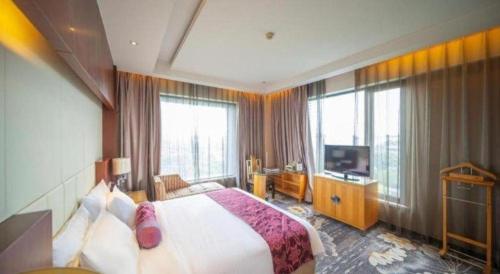 a hotel room with a bed and a television at Ramada Plaza by Wyndham Yangzhou Casa in Yangzhou