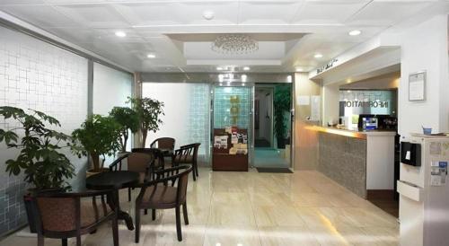 a dining room with a table and chairs and a kitchen at Hotel Casa Suwon in Suwon