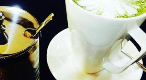 a white cup of coffee on a plate with a spoon at Oryza Hotel in Santiago City