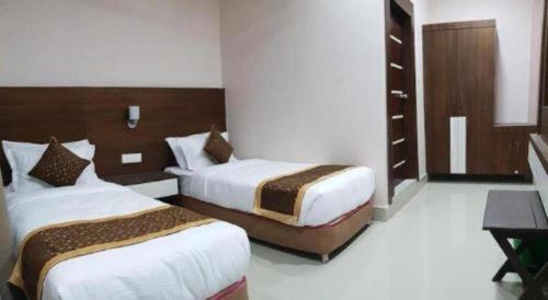 a hotel room with two beds and a desk at Hotel Gajur Palace in Itahari