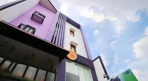 a pink and white building with a sky in the background at Oriza Hotel Surabaya in Surabaya