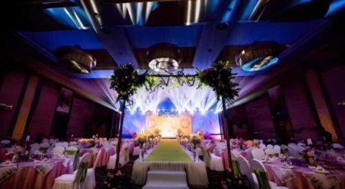 a banquet hall with tables and chairs and a stage at Qingdao Blue Horizon Hotel Licang in Qingdao