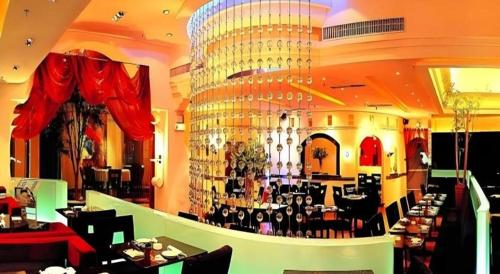 a restaurant with a bar with a large chandelier at Golden Lustre Hotel in Shenzhen