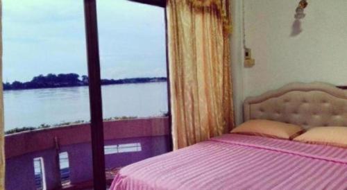 a bedroom with a bed and a large window at Just Mansion Hotel in Nong Khai