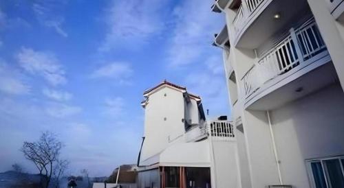 a white building with a balcony on the side of it at Gallery Pension in Taean