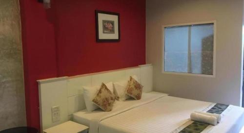 a bedroom with a white bed with a red wall at Waenpetch place Hotel in Ubon Ratchathani