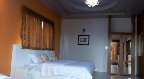 a bedroom with a white bed and a window at Waenpetch place Hotel in Ubon Ratchathani