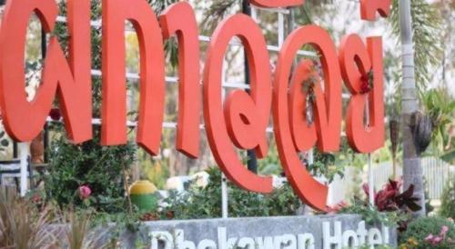 a large red sign in a garden with flowers at Phakawan Hotel in Maha Sarakham