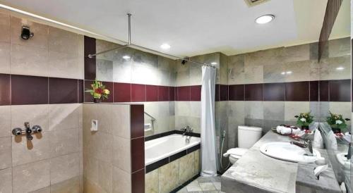 a bathroom with a tub and a toilet and a sink at Sahid Kawanua Hotel in Manado
