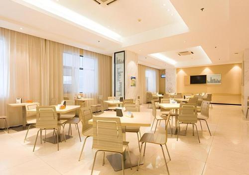 a restaurant with tables and chairs in a room at City Comfort Inn Xiangyang Railway Station in Xiangyang