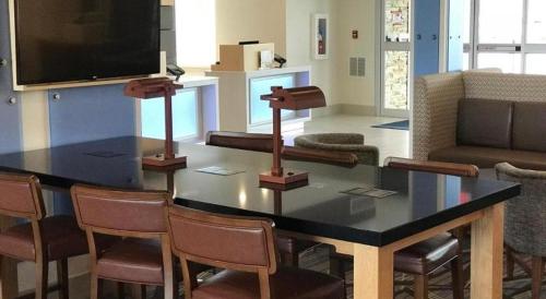 a living room with a table with chairs and a tv at Holiday Inn Express and Suites Hannibal-Medical Center By IHG in Hannibal