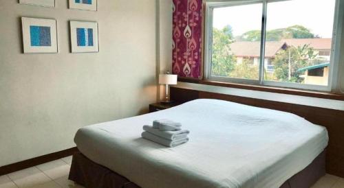 a bedroom with a bed with towels on it at Huern Che Ta One Hotel in Phrae