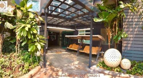 a patio with a pergola with a bed in it at Huern Che Ta One Hotel in Phrae