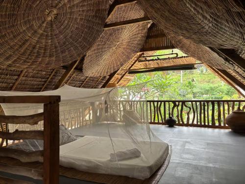 a bed in a straw roofed room with a window at Balay Asiano in Puerto Princesa City