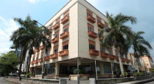 a large building with palm trees in front of it at Hotel Formosa in Manado