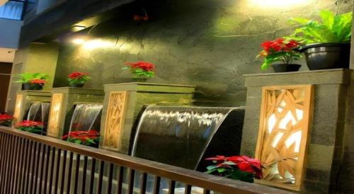 a waterfall in a building with potted plants and flowers at Lotus Hotel Subang in Bandung