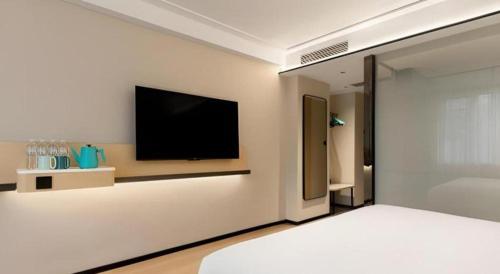 a bedroom with a tv on a wall with a bed at City Comfort Inn Wuhan Hankou Railway Station West Square in Wuhan