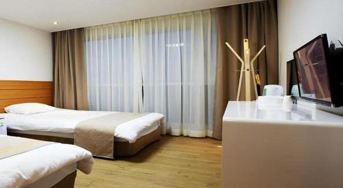 a hotel room with two beds and a flat screen tv at Ewha Hotel in Jeju