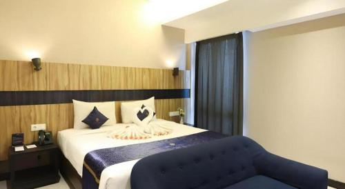 a bedroom with a large bed and a blue couch at Fitra Hotel Majalengka in Majalengka