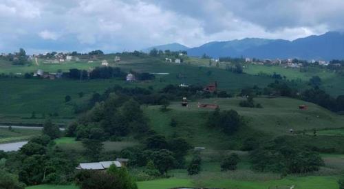 a green field with trees and houses on a hill at New Dakshinkali Village Resort in Kathmandu